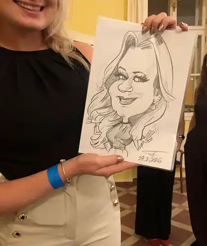 Mladá usmiata slečna pózuje a drží v rukách svoju čerstvo nakreslenú karikatúru z podujatia.